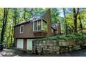 Home exterior view showcasing two garage doors, a stone retaining wall, and a partial screened-in porch at 3246 Able Ct, Marietta, GA 30062