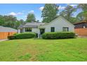 Quaint home with white painted brick, green lawn, mature trees and trimmed hedge in the front yard at 3734 Powers Ferry Nw Rd, Atlanta, GA 30342