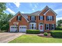 Brick two-story home features a lush green lawn, attached garage, and beautiful landscaping at 1124 Monarda Nw Way, Acworth, GA 30102