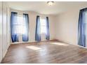 Bright bedroom featuring gleaming wood floors and three windows dressed with sheer curtains at 5136 Jones Rd, Forest Park, GA 30297