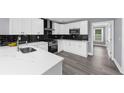 Bright kitchen with black backsplash, white cabinets, and stainless steel appliances at 4605 Tims Pl, Snellville, GA 30039
