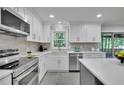 White kitchen with stainless appliances, white cabinets, tile backsplash and sliding glass doors to outdoor deck at 5400 Mill Run Dr, Marietta, GA 30068