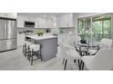 Open kitchen with stainless appliances, white cabinets and island with bar stool seating, next to breakfast nook at 5400 Mill Run Dr, Marietta, GA 30068