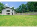 Expansive green backyard featuring a lush lawn, stone retaining wall, and terraced levels at 9701 Buice Rd, Alpharetta, GA 30022