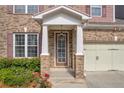 Close-up of the home's inviting front porch, showcasing brick columns, manicured landscaping, and a charming front door at 2677 Sardis Chase Ct, Buford, GA 30519