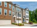 View of townhomes with attached garages, varied brick and siding, manicured landscaping, and colorful front doors at 996 Layton Dr, Buford, GA 30518
