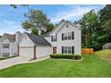 Charming two-story home featuring a well-manicured lawn, attached garage, and a vibrant red front door at 1047 Woodsong Pass Ct, Lawrenceville, GA 30043