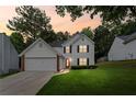 Charming two-story home featuring a well-manicured lawn, attached garage, and a vibrant red front door at 1047 Woodsong Pass Ct, Lawrenceville, GA 30043