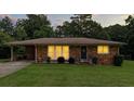 Brick house with an open carport and a well-manicured green lawn at dusk at 4065 Old Austell Rd, Powder Springs, GA 30127