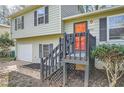 This home features an inviting front entrance with gray steps, an orange door, and muted green siding at 840 Wells Se Cir, Smyrna, GA 30080
