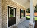 Inviting front porch with brick accents, classic columns, and a stylish black front door, creating a warm welcome at 115 Heyman Dr, Covington, GA 30016