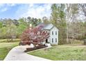 Two-story home with light green siding, black roof, and long driveway on an expansive lawn at 1772 Brittany Chase Nw, Kennesaw, GA 30152