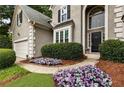 Home's manicured front entrance with colorful floral arrangements and well-maintained shrubs enhancing curb appeal at 5860 Fairway View Dr, Suwanee, GA 30024