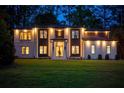 Exterior of home at dusk featuring professional lighting, white brick, wood accents, and green lawn at 942 Fairfield, Marietta, GA 30068