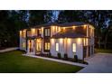 Exterior home at dusk showing professional lighting, white brick, wood accents, three-car garage and green lawn at 942 Fairfield, Marietta, GA 30068