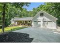 Three car garage and driveway on modern white home with welcoming front porch in lush green setting at 1031 Bailey Rd, Woodstock, GA 30188