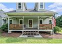 Inviting front porch with wood railing, front door with decorative glass, and classic American flag at 225 W Union Grove Cir, Auburn, GA 30011
