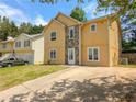 Two-story home featuring a stone facade, yellow siding, a green lawn and a concrete driveway at 2918 Pavia Circle, Austell, GA 30106