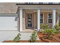 Elegant entryway featuring a black front door with sidelights, framed by white columns and professional landscaping at 910 Melody Ridge Ln, Buford, GA 30518