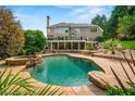 Backyard oasis with a luxurious pool, rock features, and lush landscaping at 7025 Kettering Ln, Suwanee, GA 30024