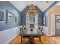 Elegant dining room with a vaulted ceiling, decorative lighting, and stylish wainscoting at 5355 Wyntree Ct, Peachtree Corners, GA 30071