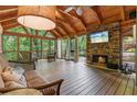 Inviting screened porch featuring a stone fireplace, comfortable seating, and wooded views at 7875 Robin Rd, Cumming, GA 30041