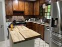 Rustic kitchen featuring wooden cabinets, stainless steel appliances, granite countertops, and a butcher block island at 170 Beatrice St, Dallas, GA 30157