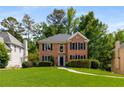 Beautiful brick home with a well-maintained lawn, mature trees, and classic architectural details, offering timeless curb appeal at 1019 Legacy Walk, Woodstock, GA 30189