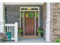Elegant front door with sidelights and transom window, framed by stone and brick accents, and potted plants for a welcoming entrance at 525 Wallis Farm Ln, Marietta, GA 30064