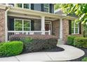 Inviting covered front porch with stone accents, white railings, and lush landscaping offers curb appeal and outdoor enjoyment at 525 Wallis Farm Ln, Marietta, GA 30064