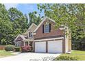 Attractive home featuring a brick and siding exterior, two-car garage, and well-kept lawn with mature trees at 1611 Hillside Bend Xing, Lawrenceville, GA 30043
