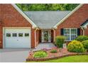 Inviting front entrance, showcases a brick facade, manicured bushes, and flower bed at 175 Prince Ct, Hiram, GA 30141