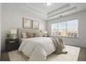 A bright main bedroom features a tray ceiling, neutral decor, and a large window offering neighborhood views at 310 Rose Garden Ln, Alpharetta, GA 30009