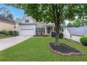 Inviting home featuring lush lawn, mature trees, and a two-car garage at 3980 Suwanee Place Dr, Suwanee, GA 30024