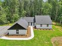 New exterior features white painted brick, vertical siding, black trim, new roof, landscaping, and wooded backdrop at 2725 Glendale Ne Dr, Conyers, GA 30013