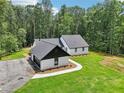 New exterior features white painted brick, vertical siding, black trim, new roof, landscaping, and wooded backdrop at 2725 Glendale Ne Dr, Conyers, GA 30013