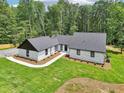 New exterior features white painted brick, vertical siding, black trim, new roof, landscaping, and wooded backdrop at 2725 Glendale Ne Dr, Conyers, GA 30013