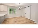Bright dining room featuring new floors, fresh paint, stylish light fixture, and convenient sliding barn door at 290 Bromack Se Dr, Atlanta, GA 30315