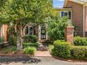 Lovely brick townhome with a brick walkway, mature tree and lush bushes leading to a decorated door at 615 Pinetree Dr, Decatur, GA 30030