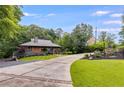 Landscaped front yard of a modern home with a long driveway and picturesque trees at 921 Oak Dr, Woodstock, GA 30189