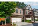 Two-story brick townhome featuring a two-car garage, well-maintained landscaping, and charming architectural details at 2021 Towneship Trl, Roswell, GA 30075