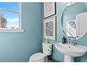 Cozy half bath featuring a pedestal sink, toilet, and tasteful decor against light blue walls at 2505 Dixon Pl, Lawrenceville, GA 30045