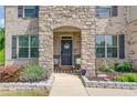 Inviting front porch with stone accents, a black door with a wreath, and decorative plants at 4931 Pauls Pointe, Sugar Hill, GA 30518