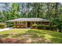 Classic brick home with black shutters, neat landscaping, and an attached carport for convenient parking at 1376 Woodbine St, Marietta, GA 30062