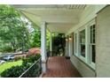 Inviting front porch with brick flooring, white columns, and lush garden views at 1276 Lanier Ne Blvd, Atlanta, GA 30306