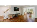 Bright living room featuring hardwood floors, an entertainment center, and access to the dining area at 8895 Club River Dr, Roswell, GA 30076