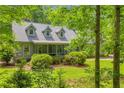 Traditional home exterior with dormer windows, covered porch, and lush green landscaping in a wooded setting at 740 Skyline Dr, Covington, GA 30014