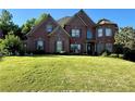 Charming two-story brick home with manicured lawn, mature trees, and an attached two-car garage at 3332 Heathchase Ln, Suwanee, GA 30024