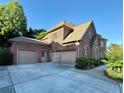 Three car attached garage featuring brick exterior with a paved drive way at 3332 Heathchase Ln, Suwanee, GA 30024