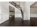 Open foyer with dark wood floors, a staircase with black railings, and paneled walls at 3415 Kenyon Creek Nw Dr, Kennesaw, GA 30152